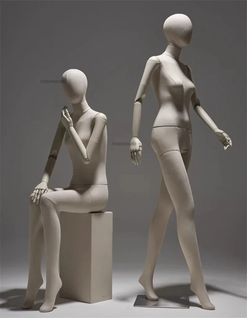 リネン布張りと木製腕の女性マネキン2体展示例|ナチュラルベージュカラー・座りポーズと歩行ポーズのディスプレイ