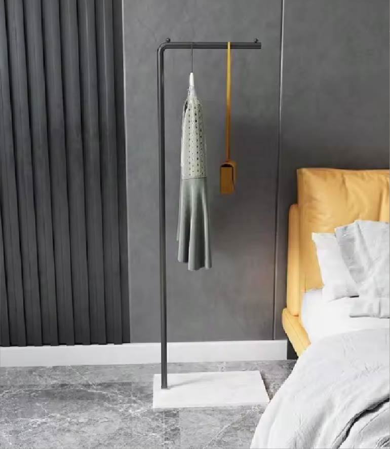 大理石ベースの黒いミニマルデザイン衣類スタンドにワンピースとバッグが掛けられている室内写真