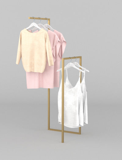 ゴールドフレームのハンガーラックに淡色トップスを掛けたエレガントなディスプレイ