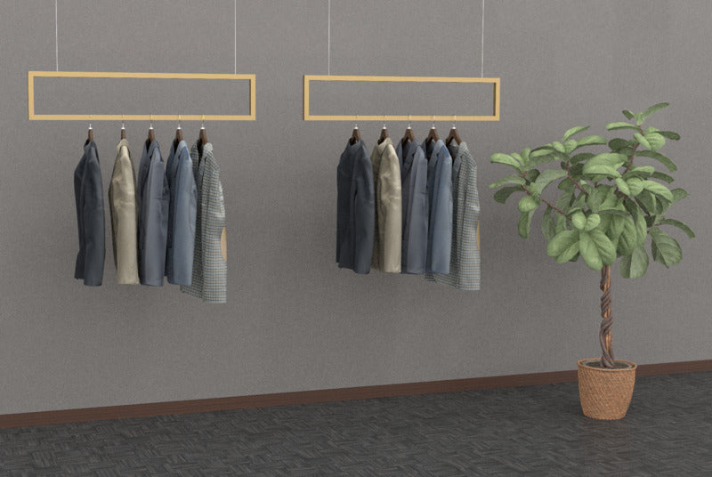 ゴールドフレームの吊り下げハンガーバーにジャケットを掛け、観葉植物を添えた店舗ディスプレイ